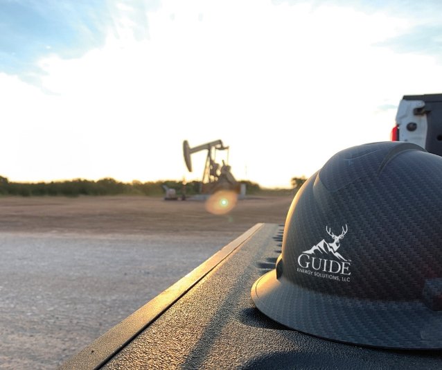 Hardhat with Guide Energy logo on site in an oil field